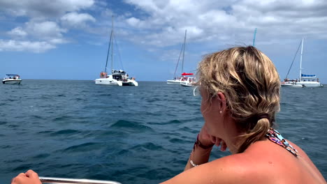 Pretty-young-girl-on-boat-watching-cute-dolphin-during-jumping-in-water