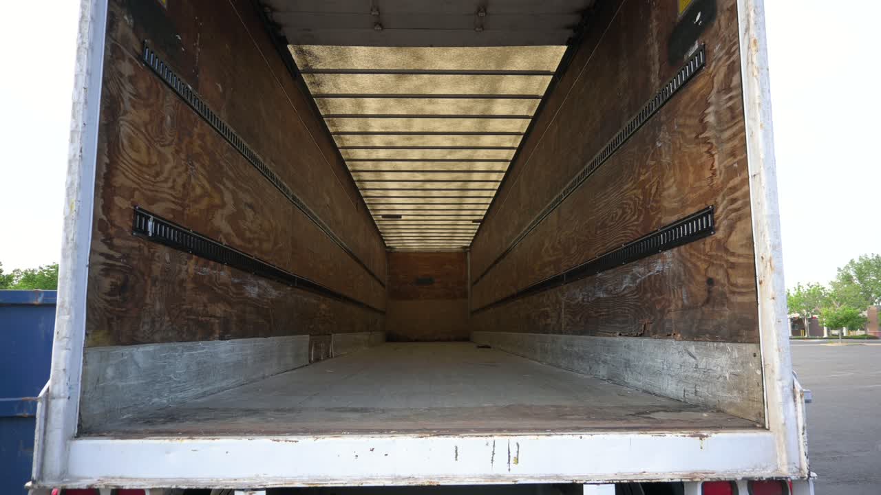 꾸러미를 받기 전에 비어 있는 흰색 세미 트럭 화물 트레일러를 들여다보고 있습니다.