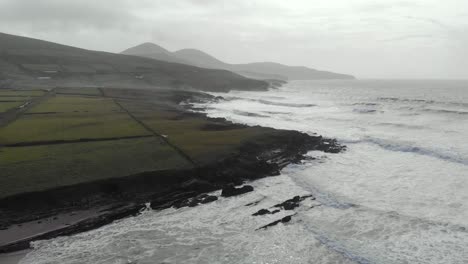 aerial of atlantic seascape next to sandy beach, waves and black rocks