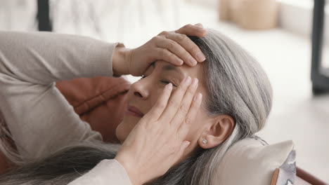 mujer enferma de mediana edad con dolor de cabeza mientras está acostada en el sofá cubierta en casa 1