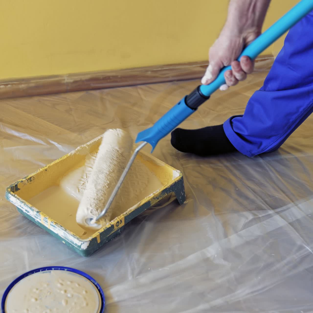 Young worker painting in room. Man painting wall during home decoration with roller brush