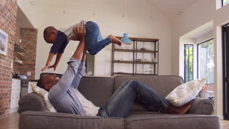 Padre-E-Hijo-Se-Divierten-Jugando-Juntos-En-El-Sofá