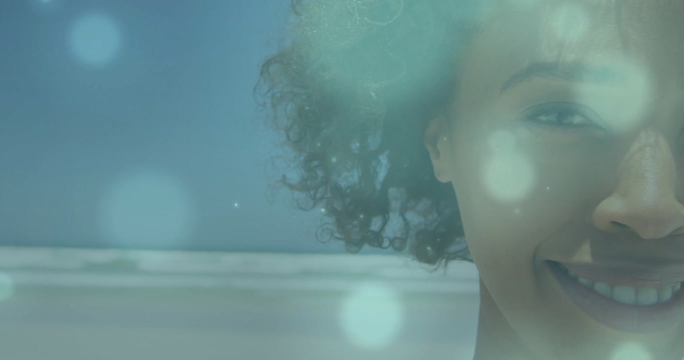 Soft light circles drifting across ocean horizon revealing smiling woman tilting head in marketing