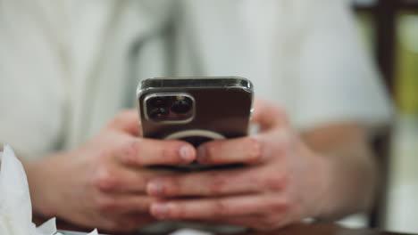 white man hand showing some reddish knuckles holding black apple phone in clear pouch while pressing screen closeup, soft background blur, focus on beauty, gesture and protective case