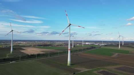 descending aerial of windmill farm next to highway in rural landscape