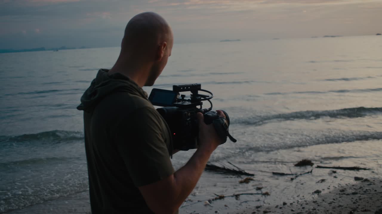 Videógrafo filmando o pôr do sol na praia