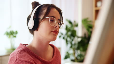 woman painting at home with headphones