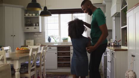 african american daughter and her father dancing together in kitchen