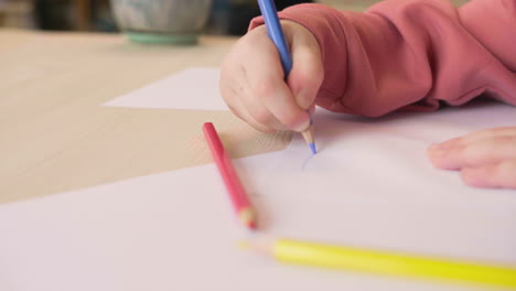 vista de cerca de una niña irreconocible dibujando en un papel sentado en una mesa en un taller de artesanía