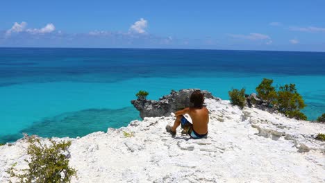 Video-Estático-De-Un-Niño-Mirando-Desde-Un-Acantilado-Hacia-El-Océano-En-Exuma-En-Las-Bahamas.