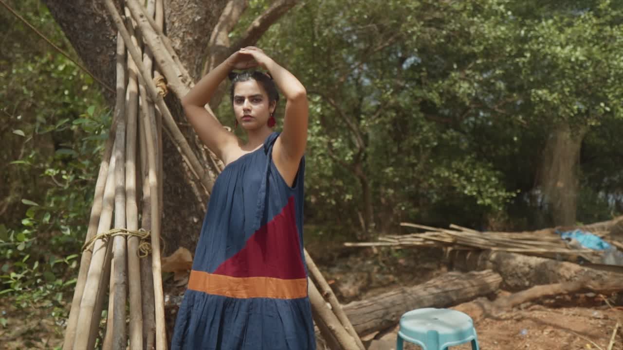 Indian fashion model posing in the forest of goa india while wearing a sustainable fashion dress in blue, red and orange in Slow Motion