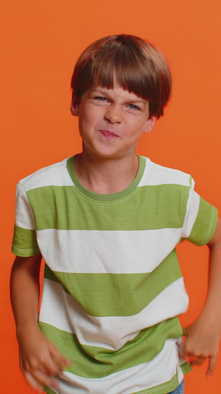 Cheerful funny bully child boy showing tongue making silly faces fooling around joking teasing