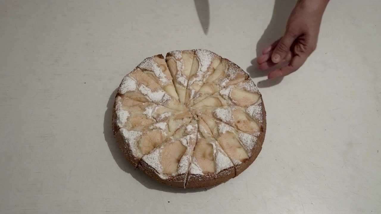 la mujer corta y toma un pedazo de pastel de manzana, que se encuentra en una mesa blanca en un plato en la cocina de la casa. vista superior. 4k.