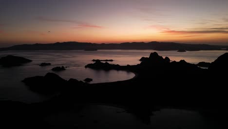 drone aerial view panning over landscapes during sunset showing silhouette island landscapes
