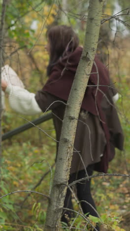 warrior girls with weapons look for traces of enemy walking between trees. female teenagers with sword and spear patrol territory checking map horizon tilts