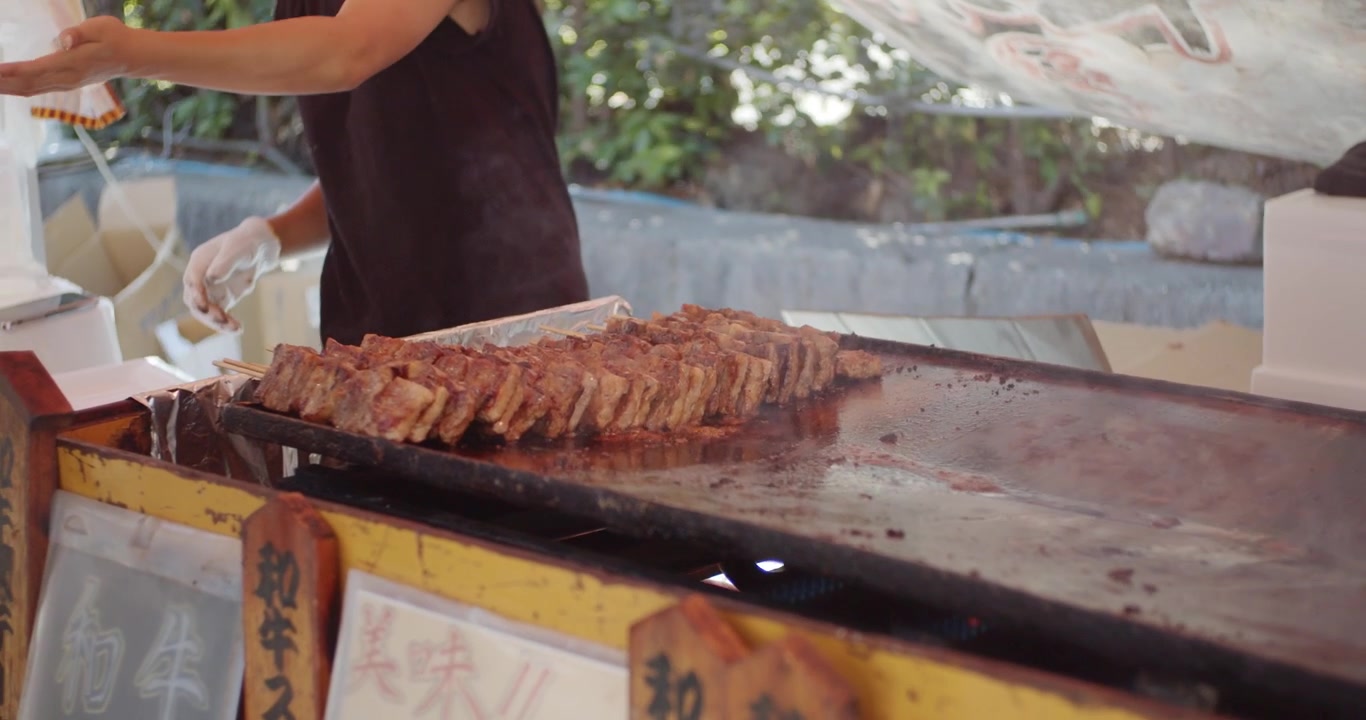 Cibo delizioso in preparazione, carne cucinata in una calda giornata estiva a un matsuri, un festival, a Kyoto, Giappone. Illuminazione soffusa, slow motion 4K