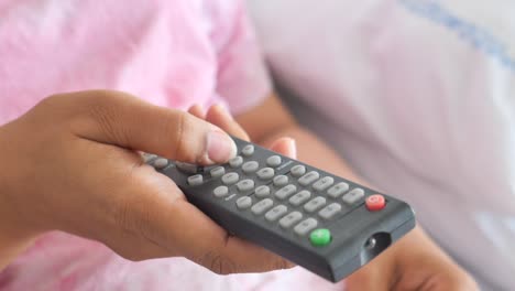 persona que sostiene un control remoto de la televisión
