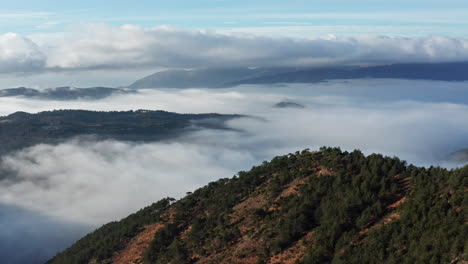 Mountainous-landscape-covered-in-clouds-with-peaks-and-trees-emerging