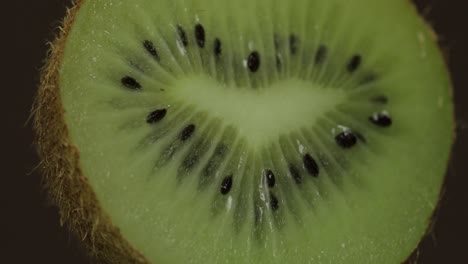 Girar-El-Trozo-De-Kiwi-Sobre-Un-Fondo-Oscuro