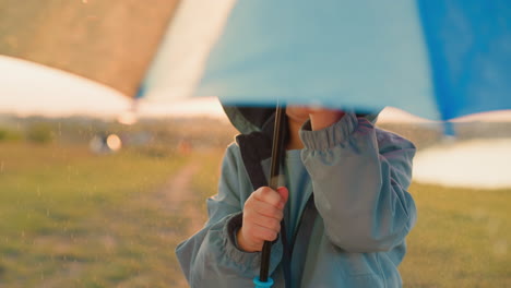 niño gira paraguas en el parque lluvioso primer plano divertido amoroso niño pequeño juega con el paraguas arco iris bajo