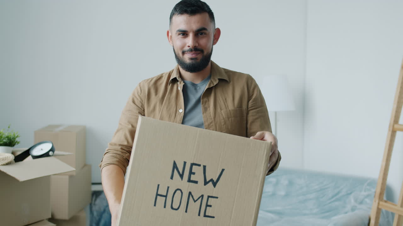 Man holding a cardboard box with "NEW HOME" written on it