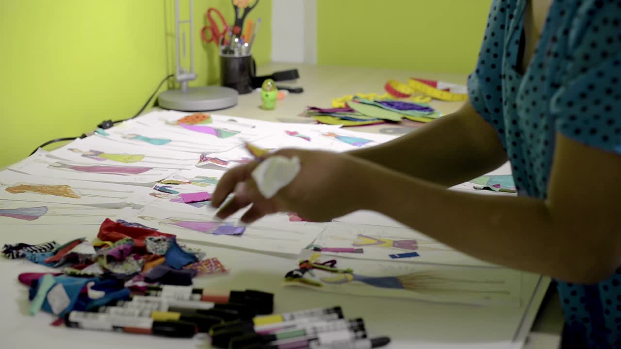 diseñador de moda latino trabajando y organizando varios bocetos para una nueva colección