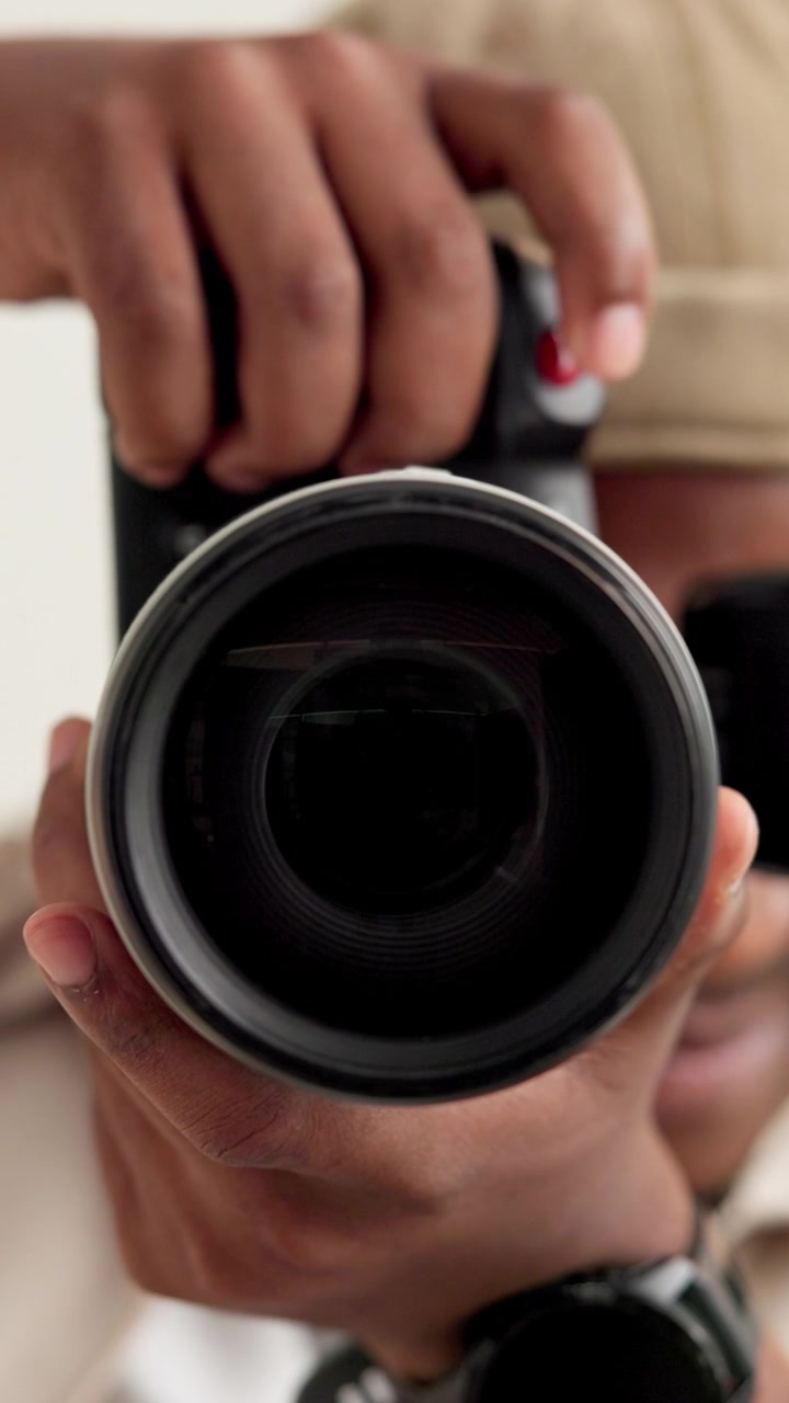 Giovane fotografo che tiene in mano una fotocamera e guarda l'obiettivo