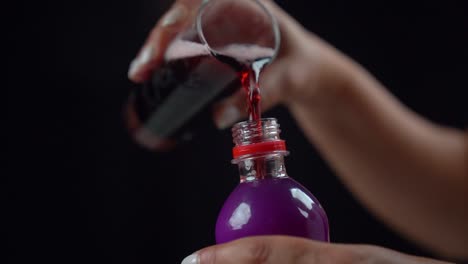 Pouring-Red-Carbonated-Soda-Drink-From-Glass-Back-Into-Purple-Plastic-Bottle