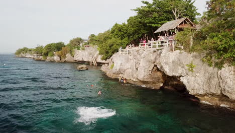 boy does flip off kalikasan cliff jump into beautiful deep blue tropical water on panglao island in the phillipines