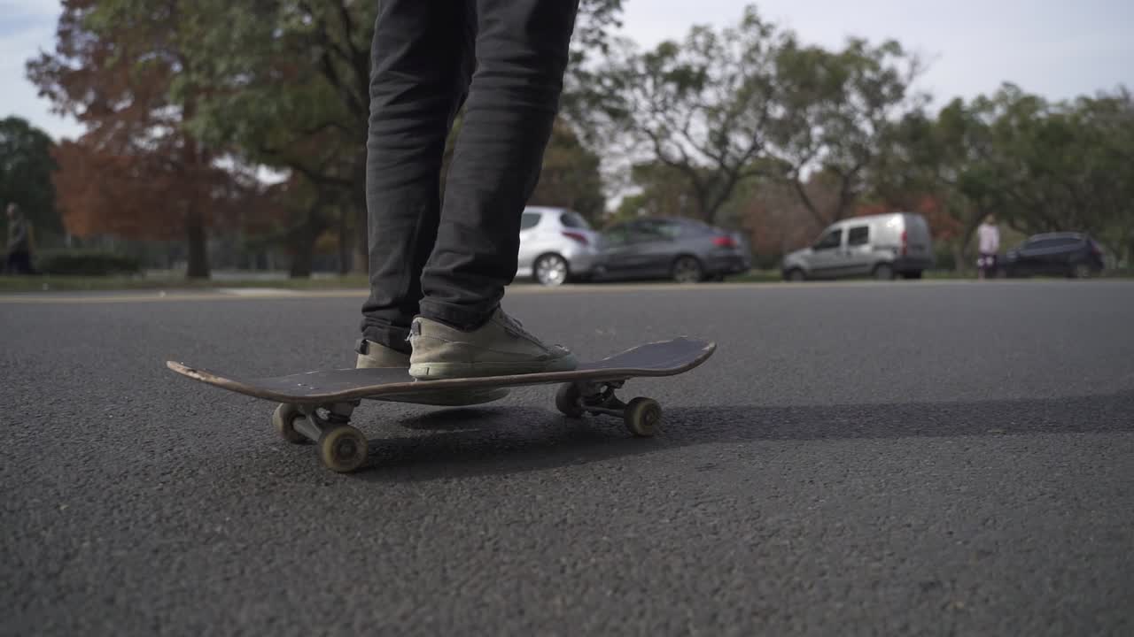 the legs and board of a skateboarder who skates past on an asphalt road in slow motion