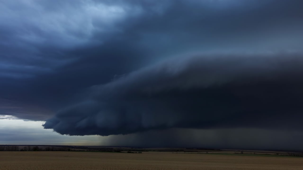 Massive Shelf Cloud Over Plains, Rolling Supercell Formation Looms Above Flat Farmland, Deep Blueblack Storm