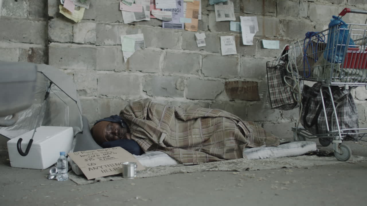 Homeless Person Sleeping on a Sidewalk with Personal Belongings