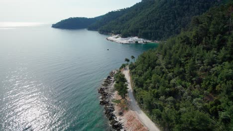 aerial view of a steep seaside rock near marble beach, surrounded by green vegetation, marble quarry in the distance, thassos island, greece, mediterranean sea, europe