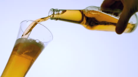 hand pouring bottle of beer into glass