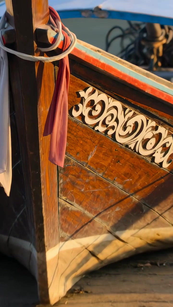 Video verticale: La telecamera si avvicina a una barca longtail in legno sulla riva, rivelando intagli e un nastro.