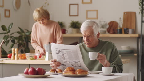 hombre anciano leyendo el periódico y bebiendo café en casa