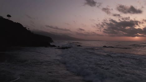 aerial view flying down mountain range dramatic sunset coastal beach seascape horizon