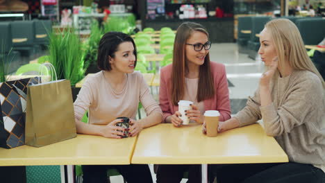 three women friends enjoying coffee in a shopping mall