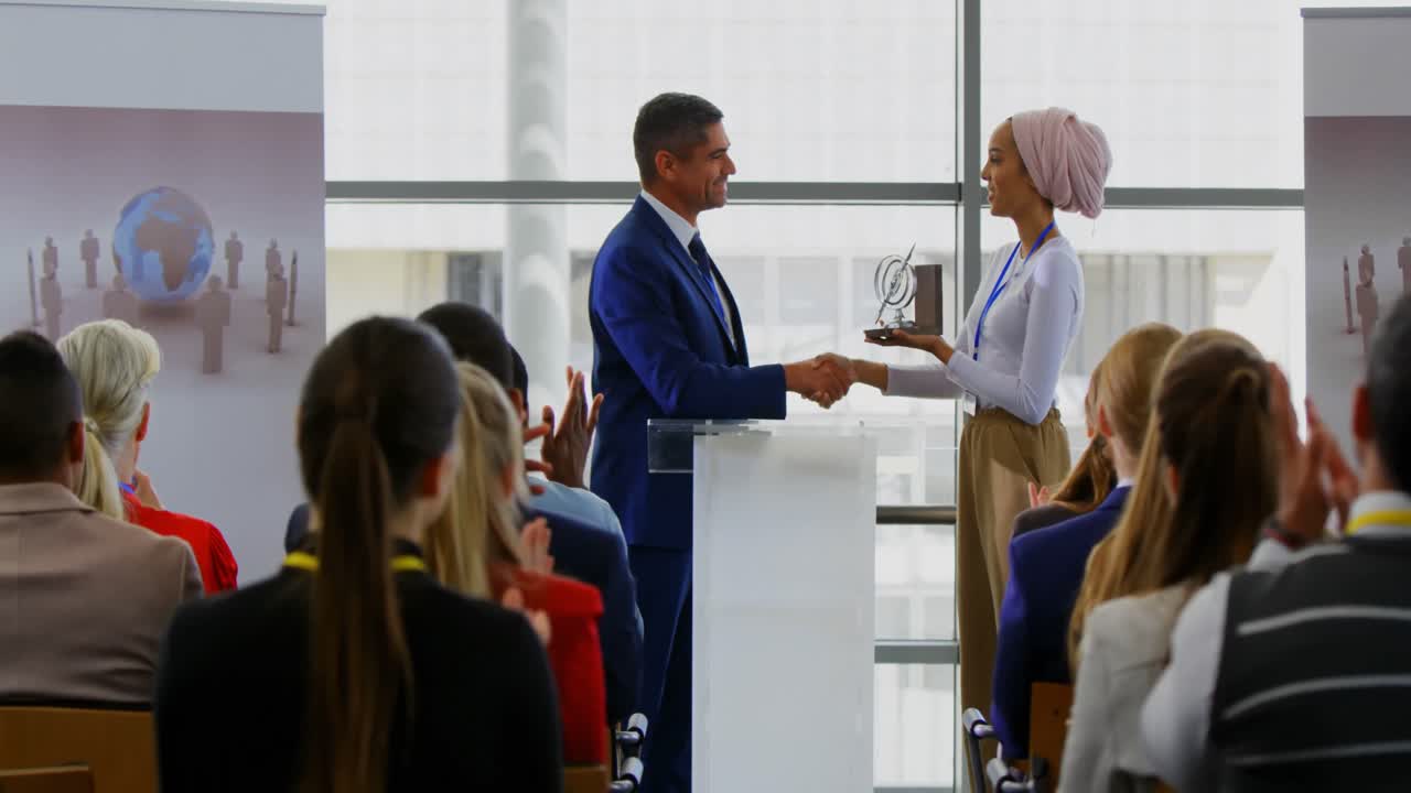 hombre de negocios recibiendo un premio de una mujer de negocios en el seminario de negocios 4k
