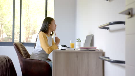 studying at desk, girl using laptop with notebook and orange juice nearby
