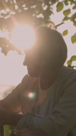 el dueño del perro en cuclillas en un campo cubierto de hierba frotando cariñosamente la oreja del perro con un guante de aseo mientras sostiene la correa, bajo la cálida luz del sol creando un hermoso efecto de silueta, con un fondo borroso
