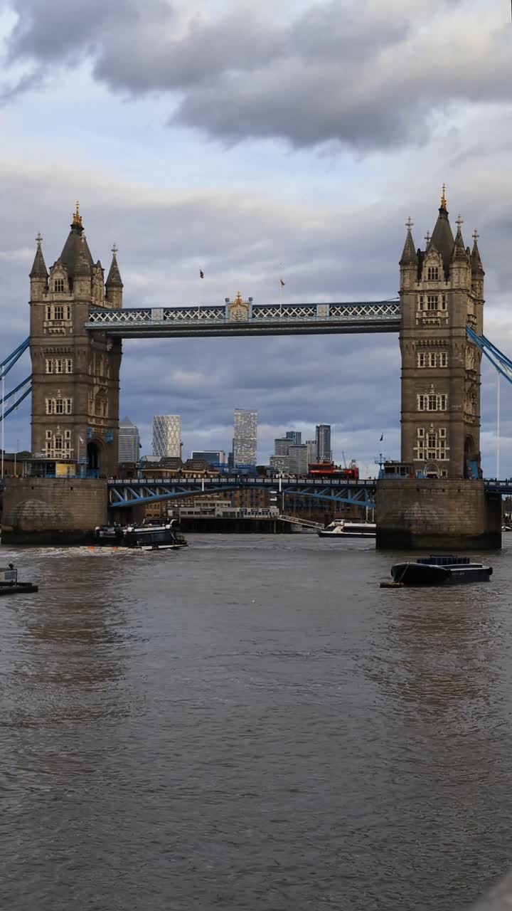 Vertikal video til sociale medier, der viser Tower Bridge i London over Themsen med historiske tårne, byens skyline, overskyet himmel og roligt vand, hvilket skaber en ikonisk udsigt over et bylandemærke.