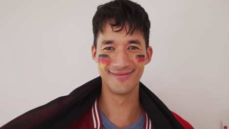 portrait of happy biracial man with national flag and flag of germany on cheek