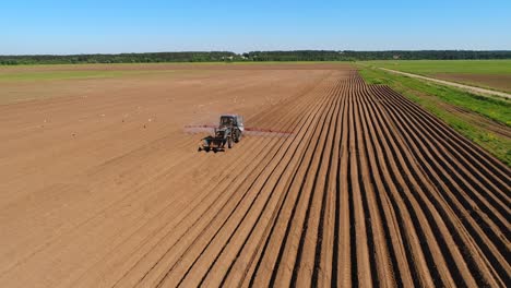 un agricoltore su un trattore spruzza campi arati con fertilizzanti e sostanze chimiche