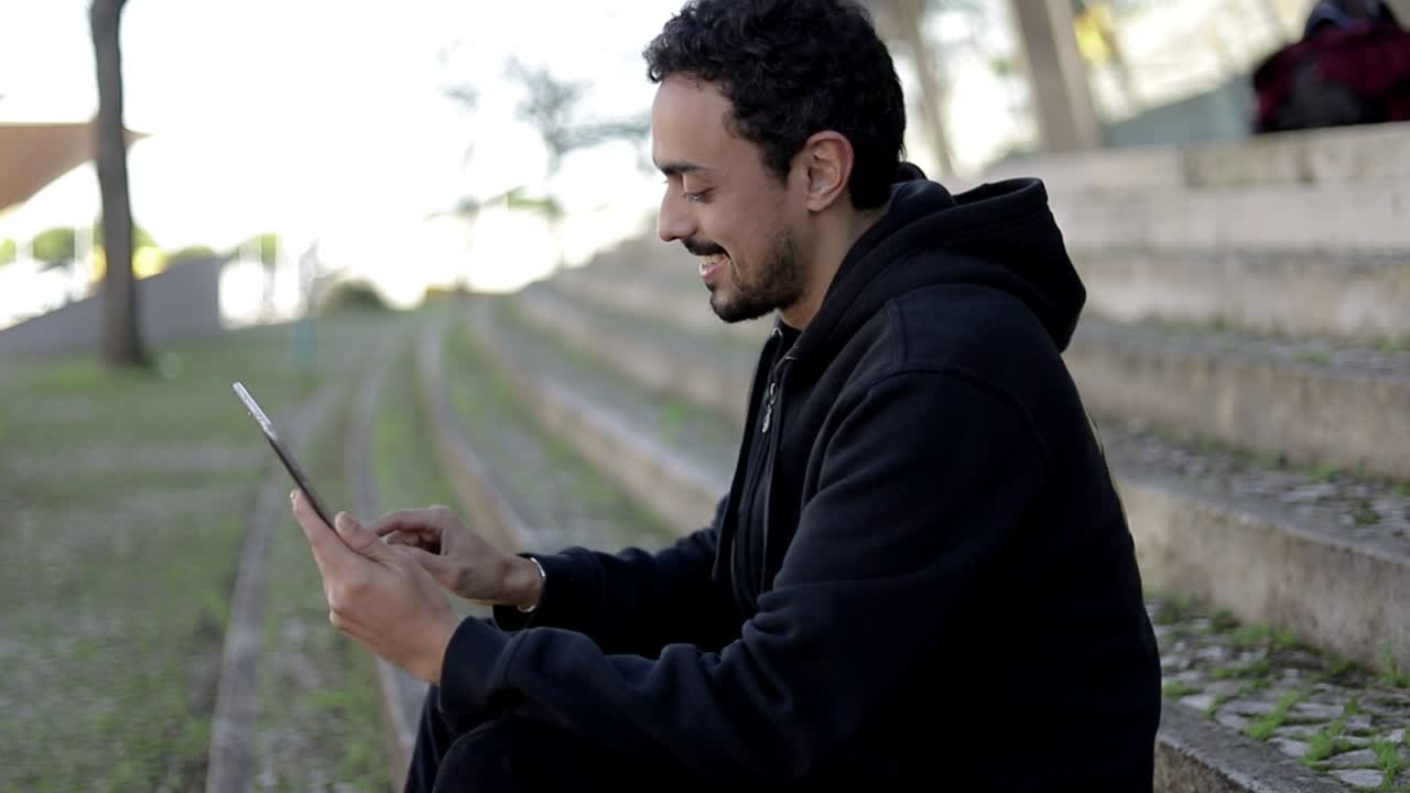 Felice giovane uomo utilizzando la tavoletta digitale