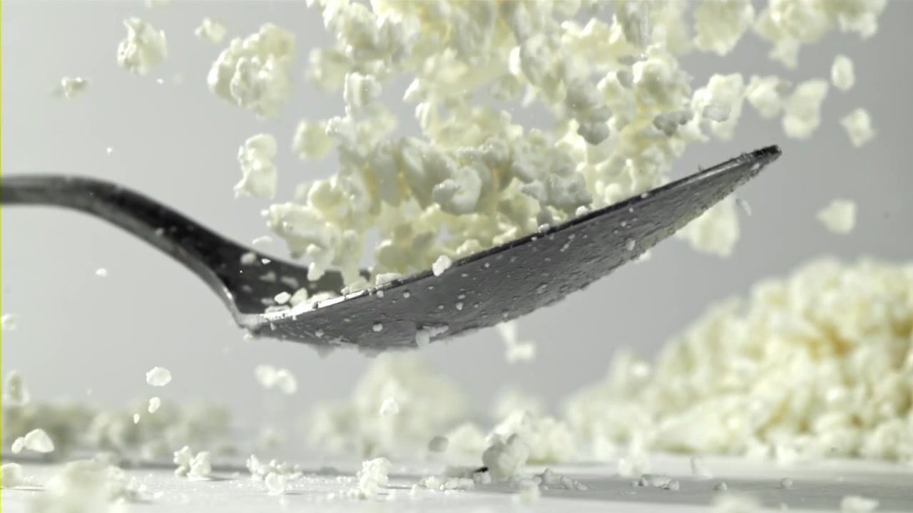 Fiocchi di latte che cadono da un cucchiaio al rallentatore