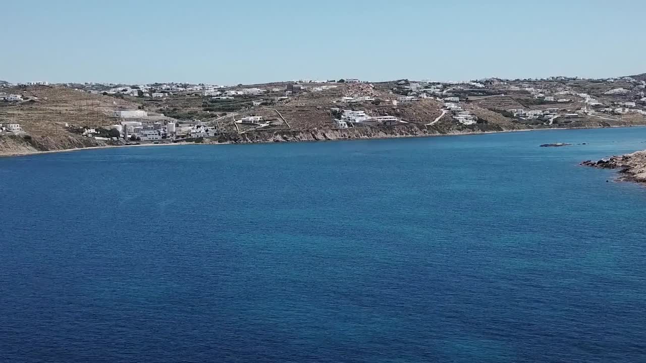 drone aéreo moviéndose hacia atrás playa mykonos agua azul