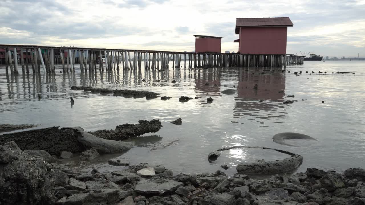 해안가에 있는 오래된 자동차 타이어. 배경은 클랜 제티에 있는 나무 다리입니다.