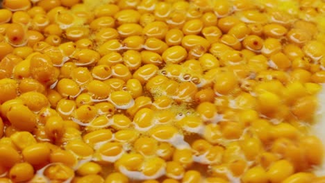 bayas saludables de espino marino para beber té, bayas maduras congeladas en frasco de vidrio y ramas con hojas vista superior en fondo rústico de madera oscura, genial para la piel, el corazón, los vasos y el sistema inmunológico.