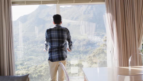 hombre afroamericano disfrutando de la vista soleada de las montañas desde la ventana de su casa, espacio de copia, cámara lenta